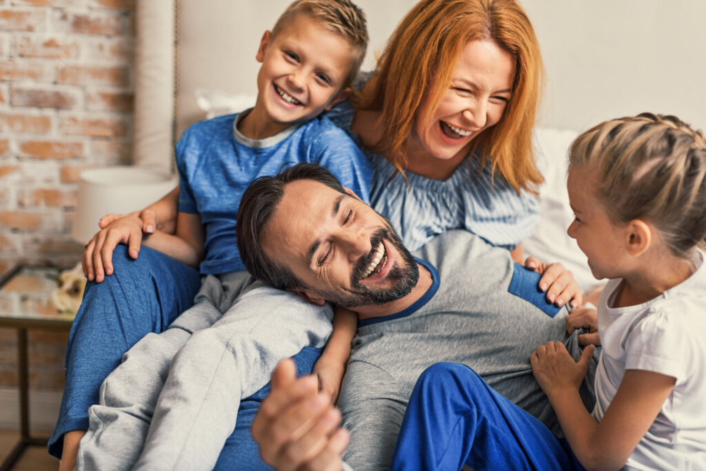 young smiling family of four having fun while lying on bed