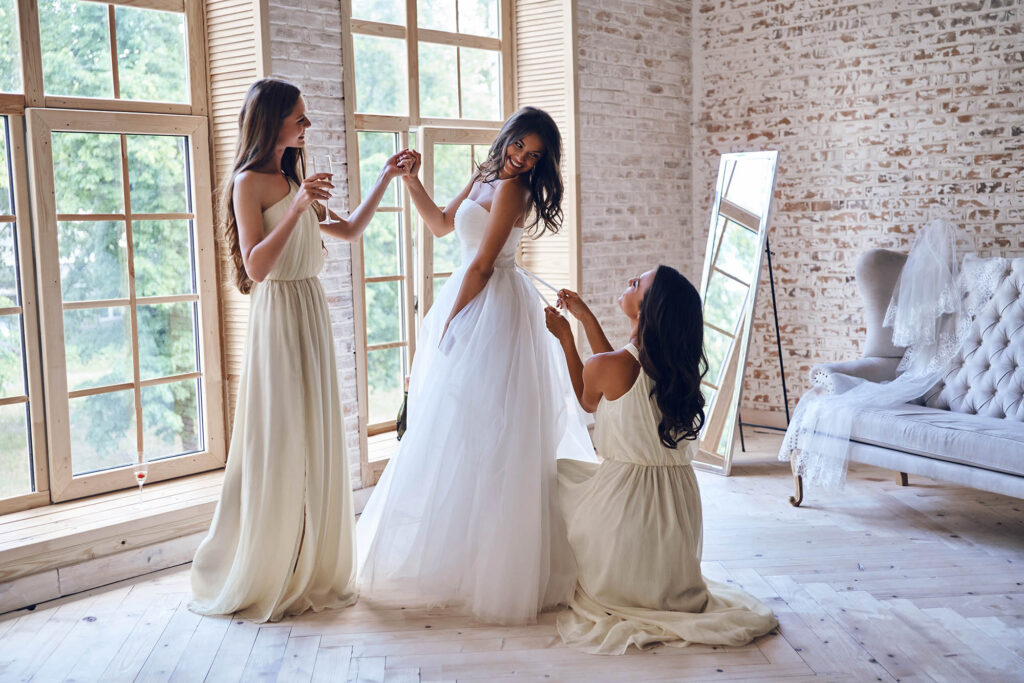  Full length of two attractive young women adjusting a wedding dress on a